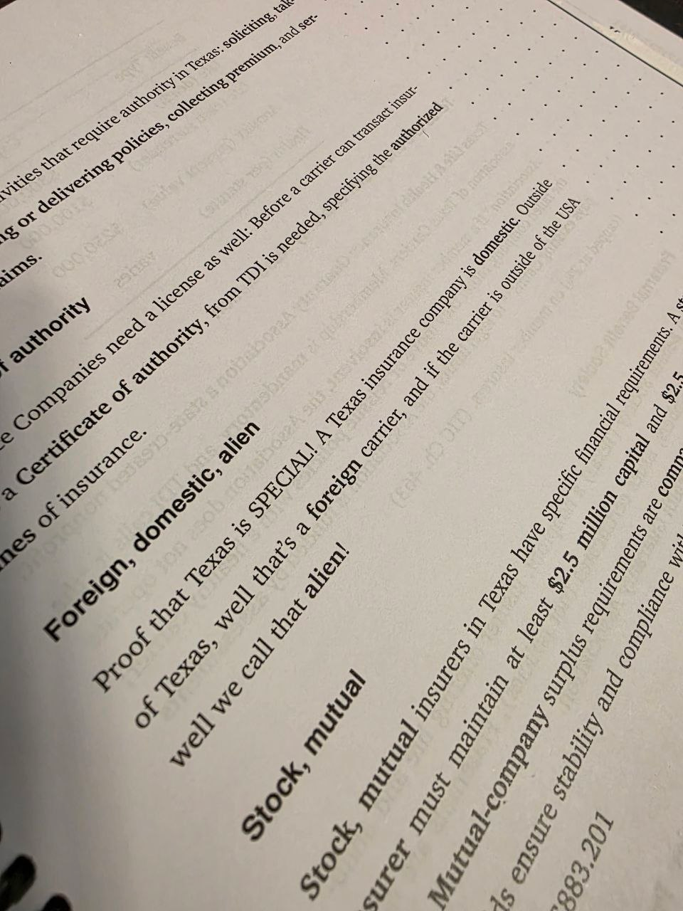 Photograph of a spiral-bound textbook explaining foreign, domestic and alien insurance companies